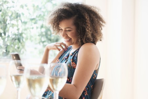 Young woman using smart phone at restaurant.
