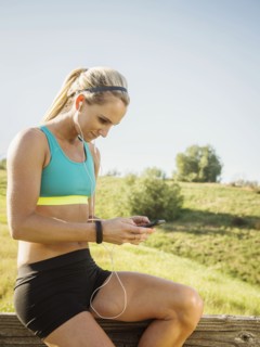 Woman sitting on fence, using smart phone