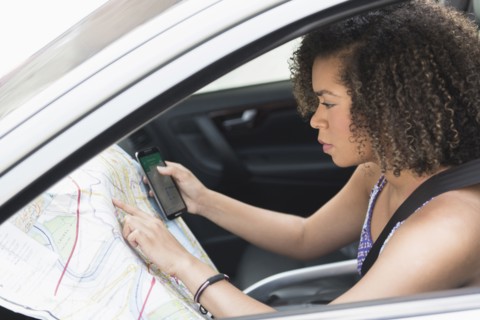 Young woman checking map in car.