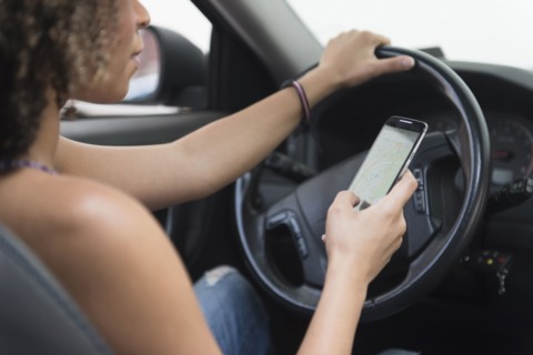 Young woman texting while driving car.