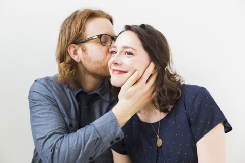 Man kissing smiling young woman