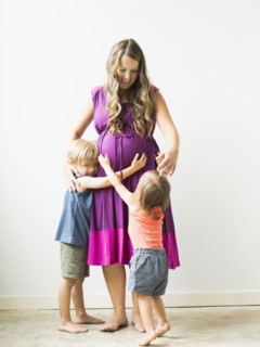 Children (2-3) hugging pregnant mother