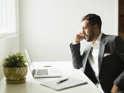 Young man sitting at desk and looking at laptop