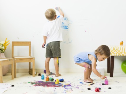 Children (2-3) painting on carpet and wall