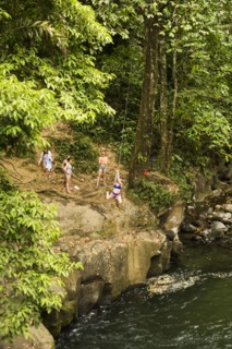 Women swinging on rope swing above river in distance