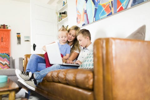 Mother with children (4-5, 6-7) using laptop on sofa