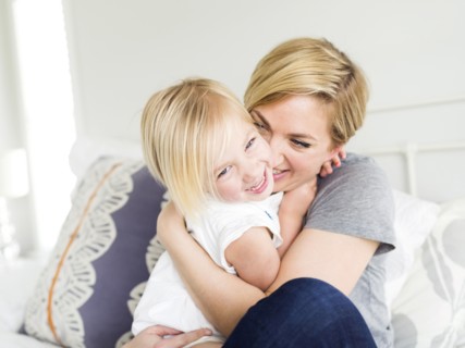 Woman hugging daughter (2-3) in bedroom