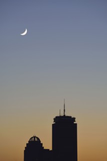 Crescent moon above office buildings