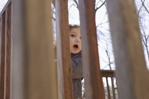 Portrait of girl hiding behind fence