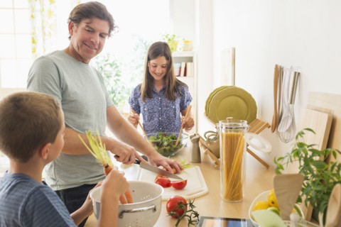 Children (8-9, 10-11) preparing food with their father.