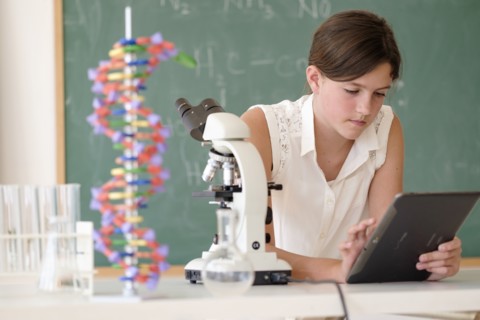 Girl (10-11) using tablet pc in classroom.