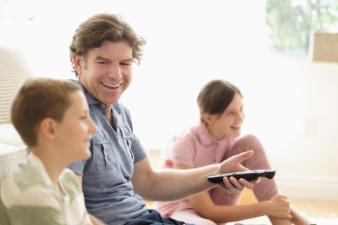 Children (8-9, 10-11) watching TV with their father.