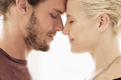 Couple rubbing noses on white background.