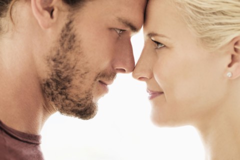 Couple rubbing noses on white background.