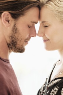 Couple rubbing noses on white background.