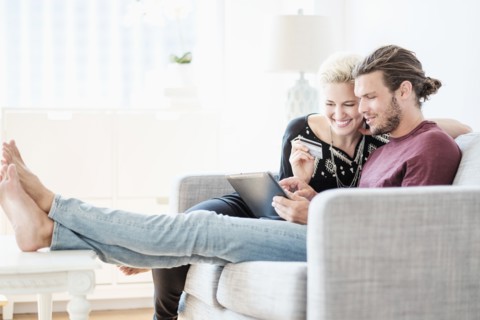 Couple using tablet pc on sofa.
