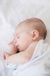 Baby girl (2-5 months) sleeping on bed