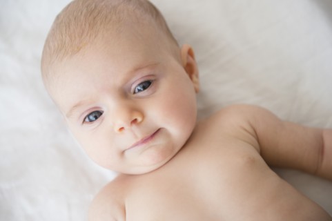Baby girl (2-5 months) lying on bed