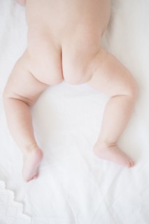 Baby girl (2-5 months) crouching on bed