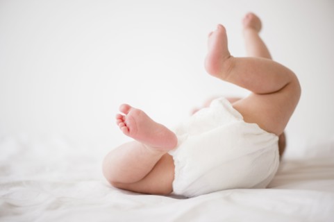 Baby girl (2-5 months) lying on bed