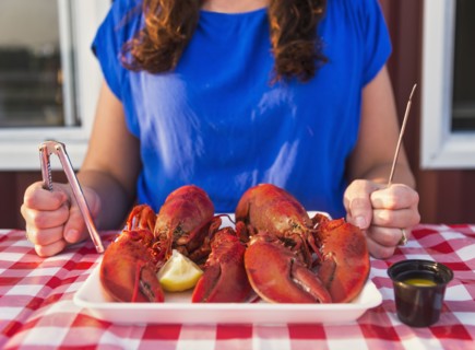 View of table with lobster meal and woman preparing to eat