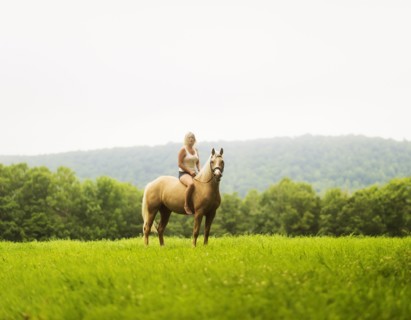 Woman horseback riding in countryside