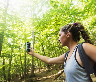 Female hiker looking at compass on phone