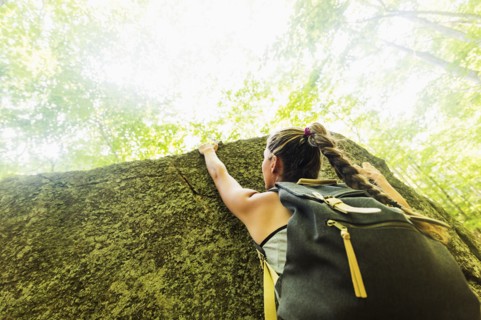 Young woman climbing on rock in forest