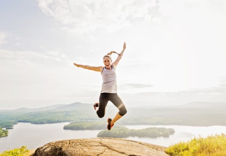 Young woman jumping over mountain top
