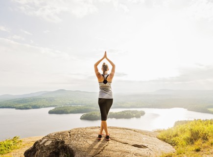 Rear view of young woman practicing yoga in front of lake