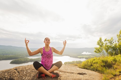 Young woman in lotus position against lake