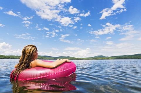 Young woman relaxing on lake in pool raft