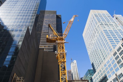 Low angle view of crane among skyscrapers