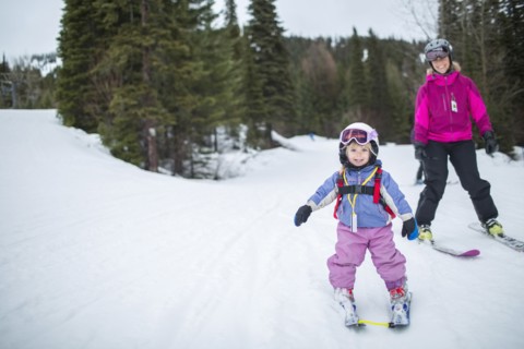 Little girl (2-3) learning skiing with mother