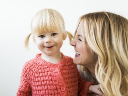 Cute girl (2-3) smiling at camera with mother