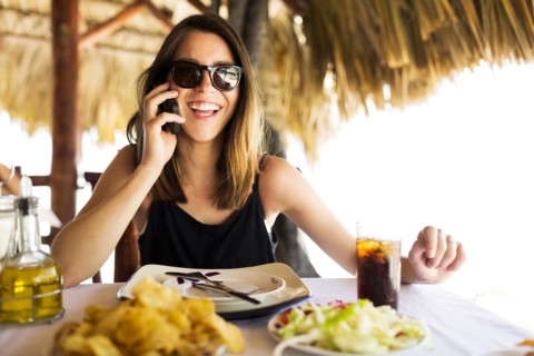 Woman by table, using phone