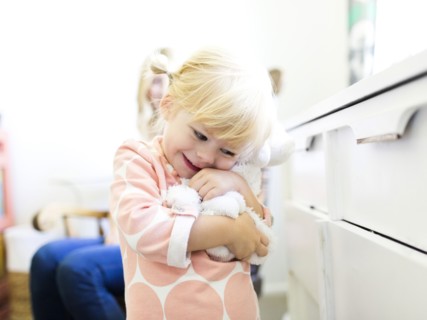 Girl (2-3) embracing toy
