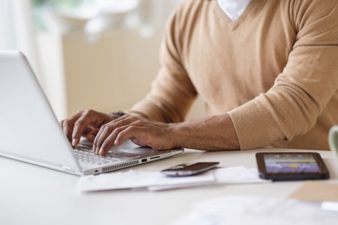 Man working with laptop at table at home.