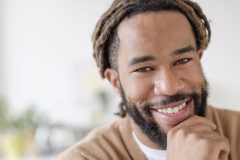 Portrait of smiley young man with hand on chin.