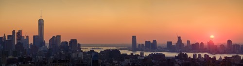 Waterfront cityscape under golden sky at sunset. New York City, New York, USA.