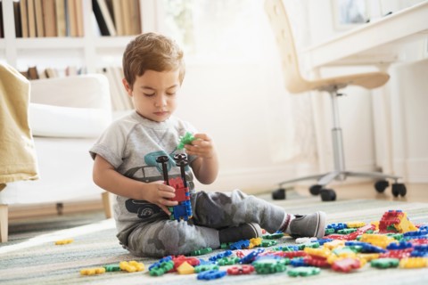 Boy (2-3) playing with toy blocks.