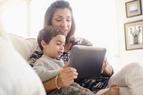 Mother reading with son (2-3) on sofa.
