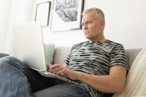 Man sitting on sofa using laptop.
