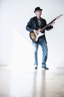 Man playing bass guitar in empty room.