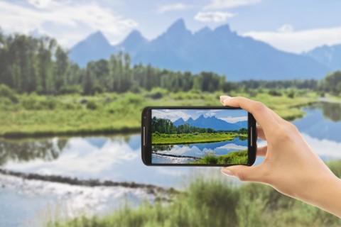 Hand photographing lake. Grand Tetons, Grand Teton National Park, Wyoming, USA.