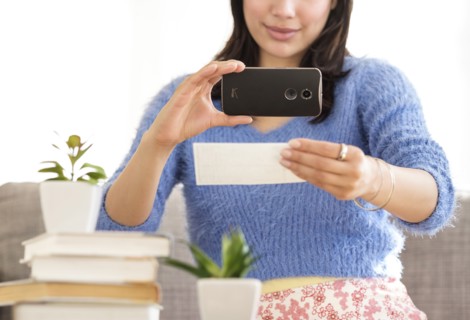 Young woman photographing bank statement.
