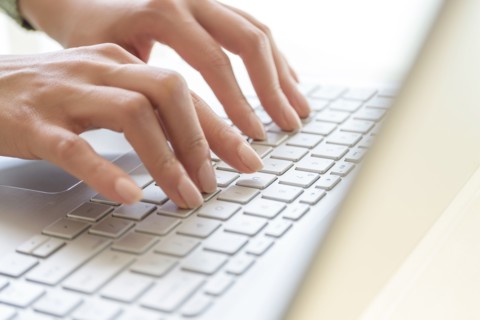 Hands typing on laptop keyboard.