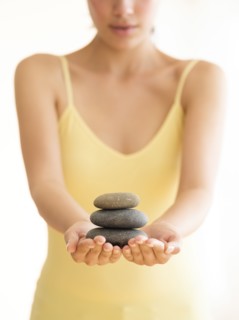 Woman holding stack of pebbles.