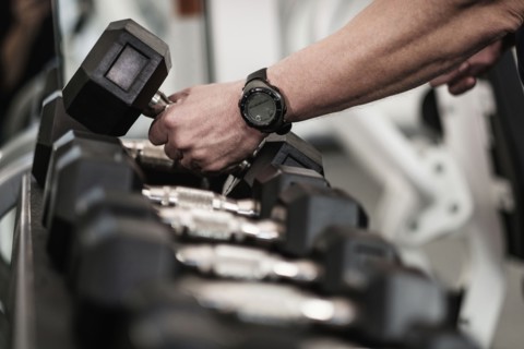 Man picking up dumbbells in health club.