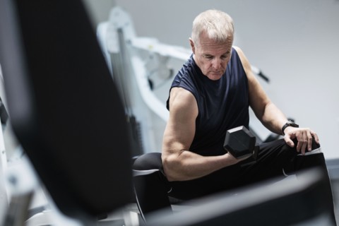 Man exercising with dumbbells on weight bench.